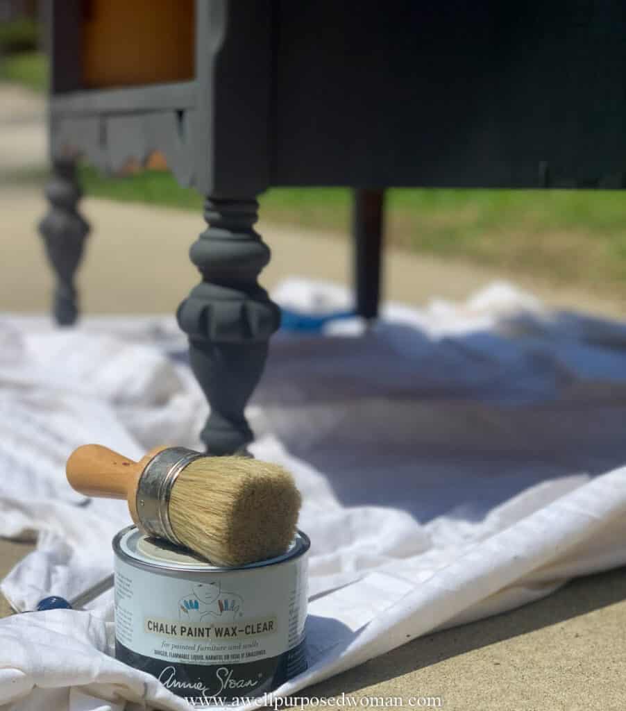 Annie Sloan wax with natural bristle wax brush in front of the black chalk paint dresser legs